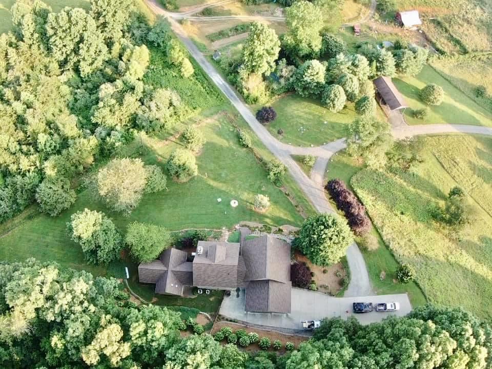 aerial photo of entire home taken from directly above the roof. This shows the extension roof in a cross pitch roof system, the middle living section of the two story part of hte home with a pitch roof, the connecting enclosed breezeway and the workspace and attached area of the garage.