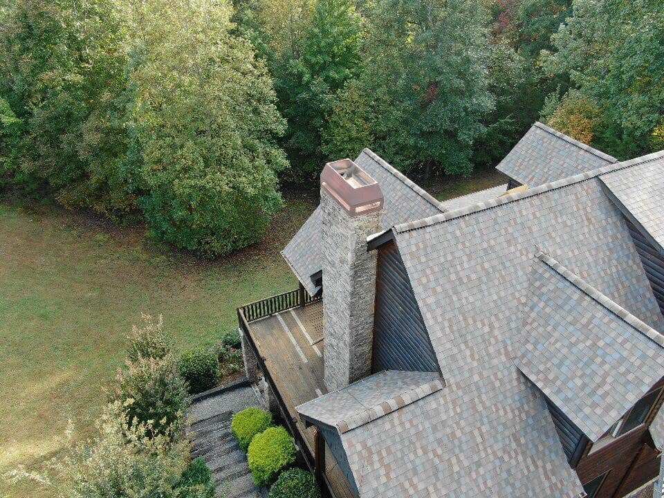 aerial photo of an expansive home with multiple pitched dormers with brown and blue tiles