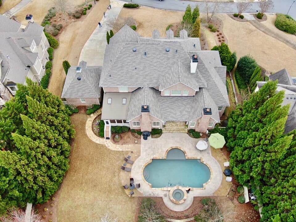 Aerial photo of estate home with large in ground swimming pool in back yard.