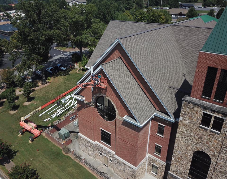 aerial photo of edging and trim work on front of church using the crane to hoist team and equipment and materials