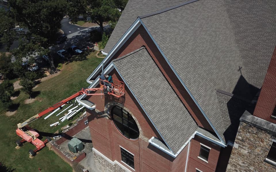 aerial photo of team on crane installing the edging and finishing sides of the new roof.