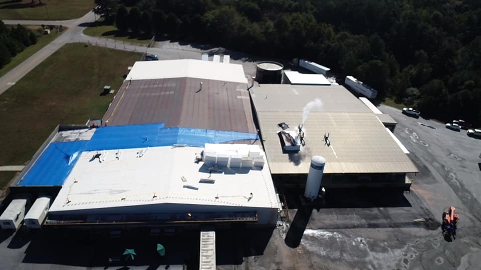 longer view of plant with large sections of blue tarps covering the damaged areas of the roof