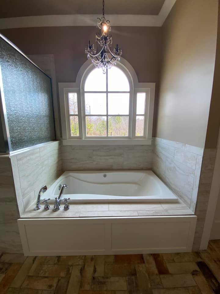 Photo of master bedroom soaker tub with chandelier and arched window