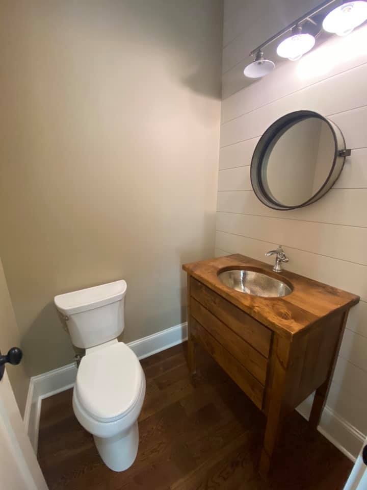 Photo of gust bath with rustic sink and mirror. large beadboard wall and rustic lighting