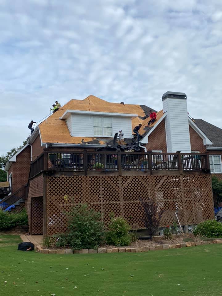 photo of rear of Watkinsville home with workers starting to install underlay system