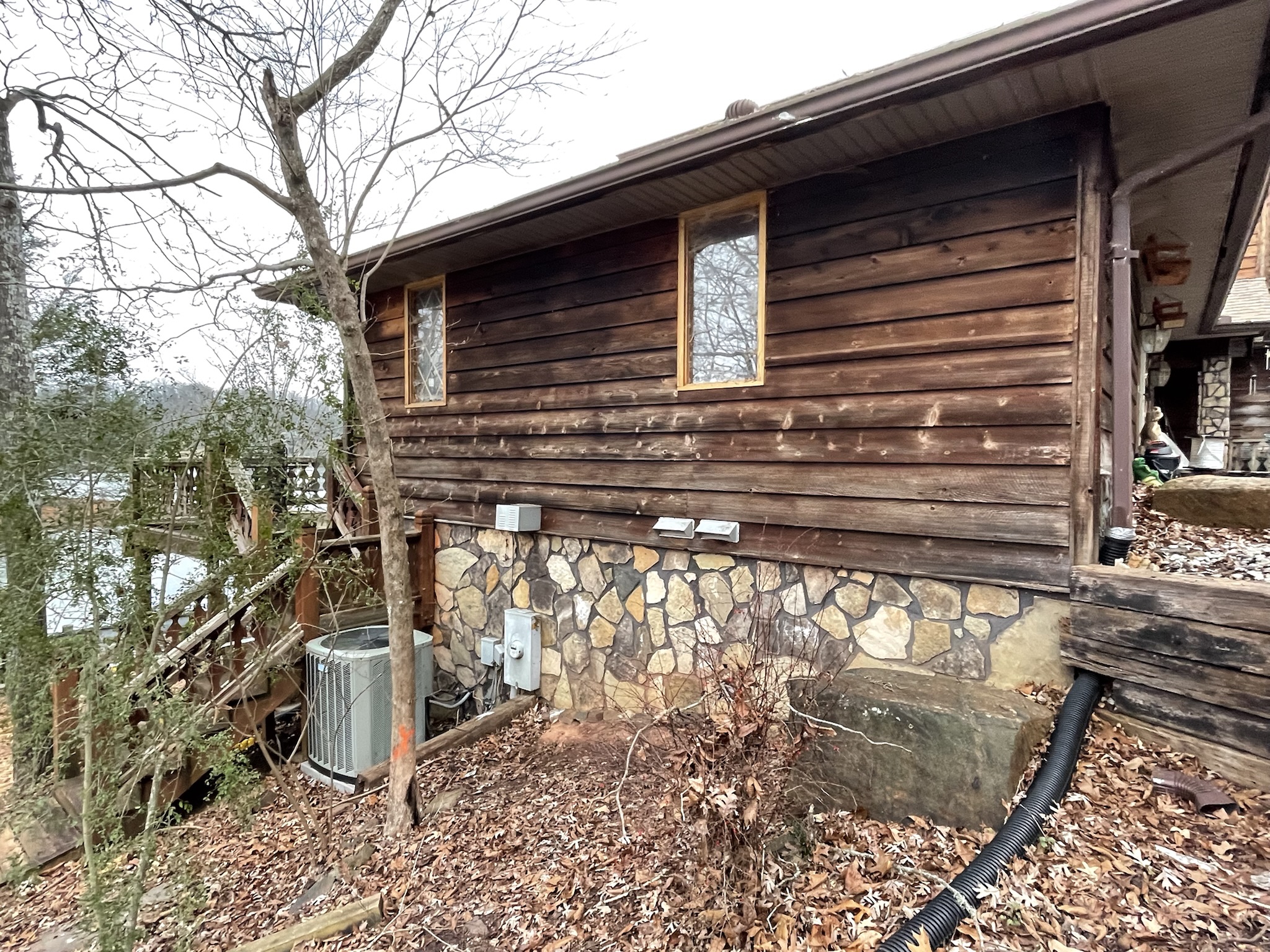 Photo of original house showing exterior log wall with exposed drainage pipes