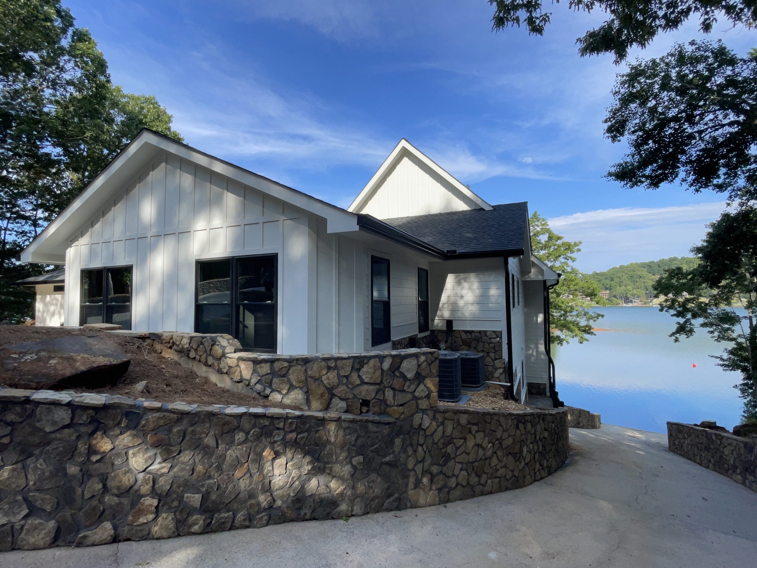 Photo of front of the home showing the paved drive down to the dock level along with stone patios leading to side door and garage