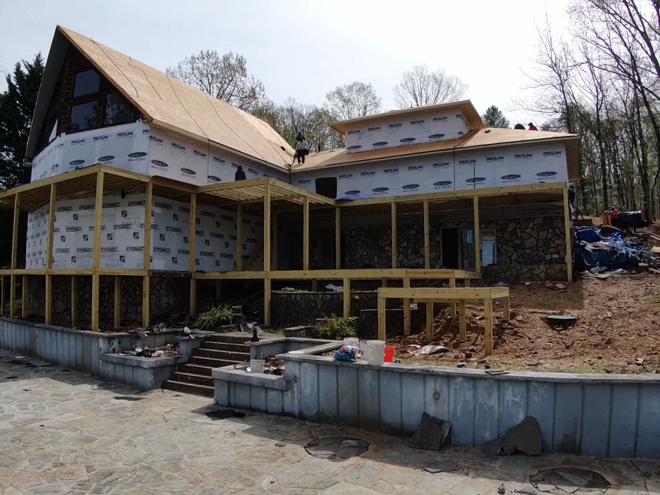 photo of rear of home during major construction of the roofing, decking and prior to installation of retaining walls